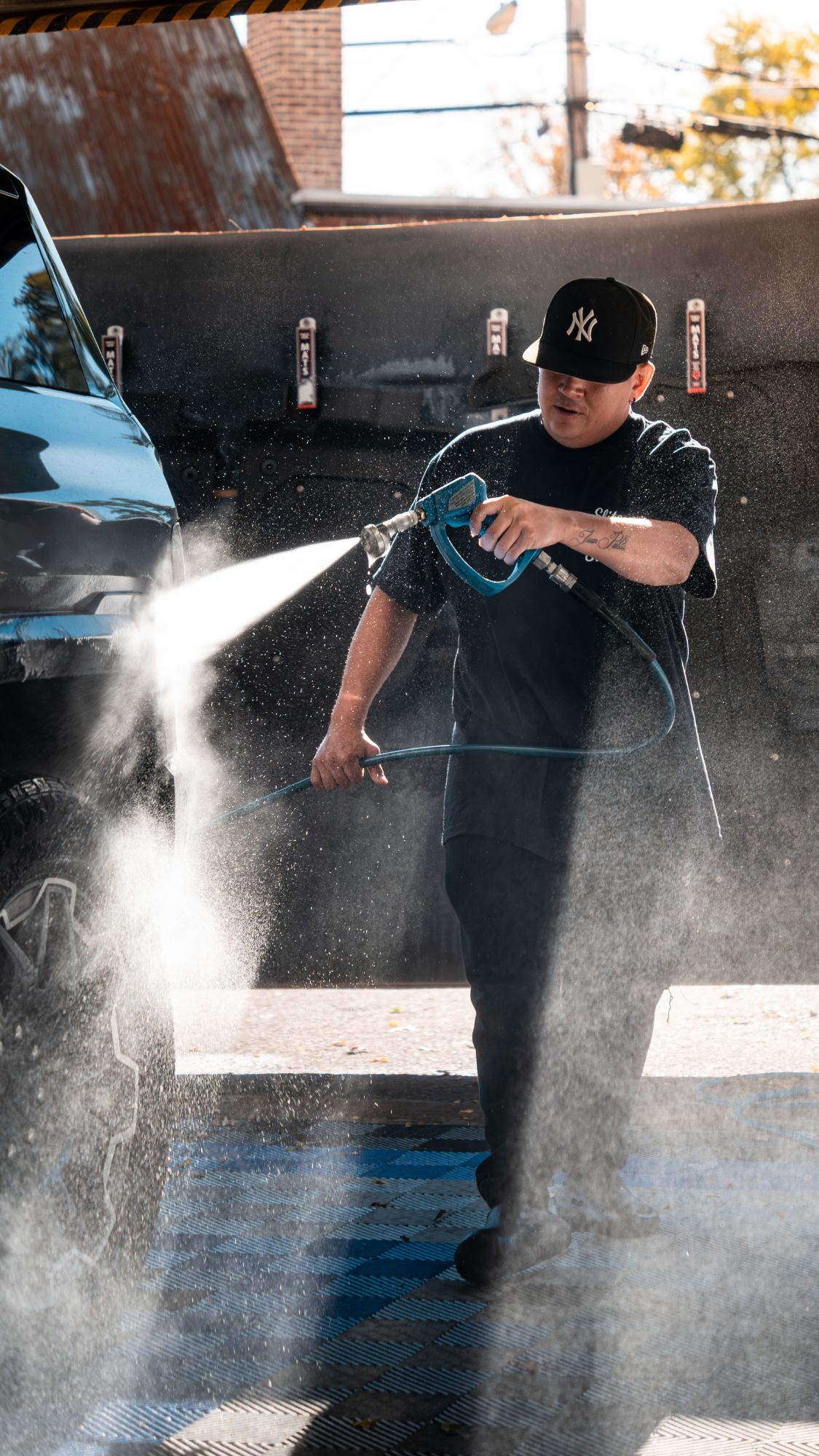 Elite Detail Studio content shoot: a detailer pressure-washing an SUV
